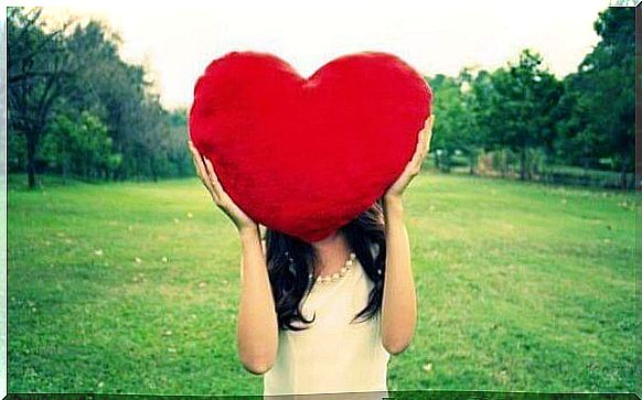 A woman holding a big red heart over her head