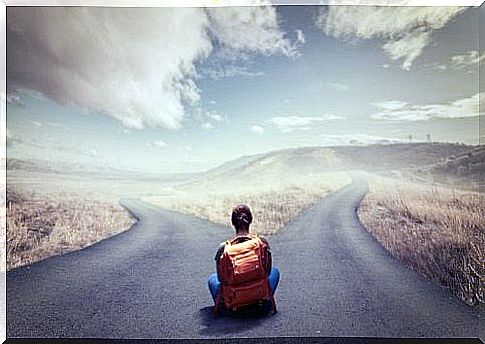 A woman with a backpack is sitting at an intersection