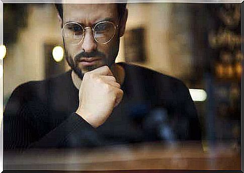 A guy with glasses thinking in a window