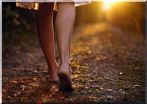 A woman walking barefoot on a path outdoors