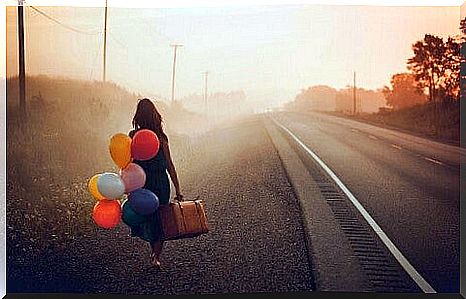 Woman with balloons and suitcase can see hope in the dark