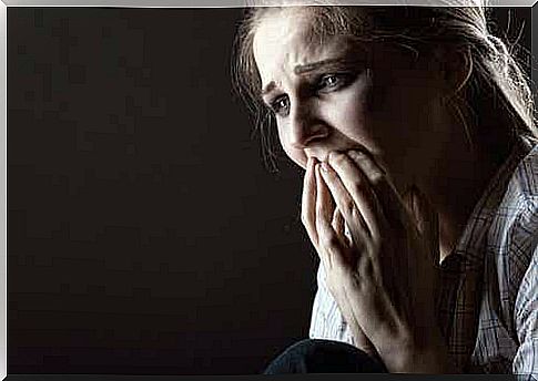 A scared woman covering her mouth with her hands.