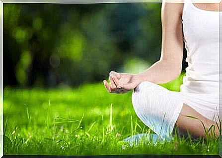 A woman meditates in the grass