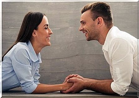 A man and woman holding hands and talking to each other, smiling