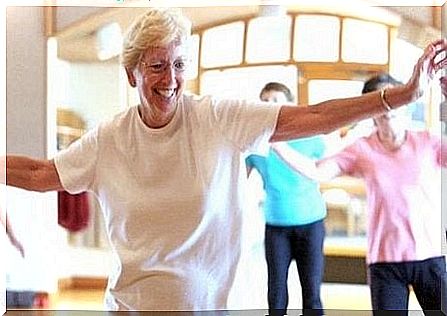 An elderly woman dances with a smile on her face