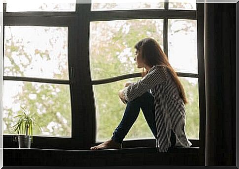 A sad woman looking out the window and considering her life.