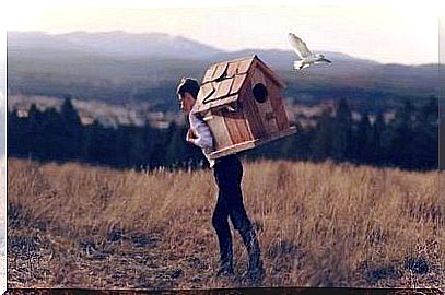 Man carrying a birdhouse on his back.