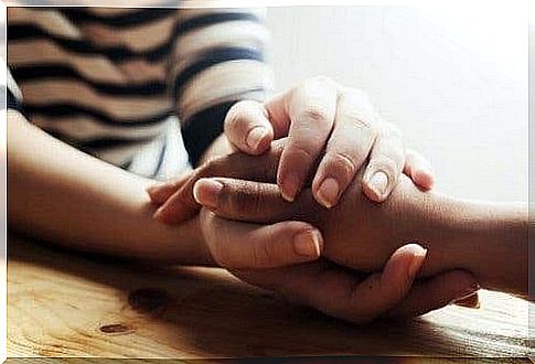 Two people holding hands and showing more compassion.