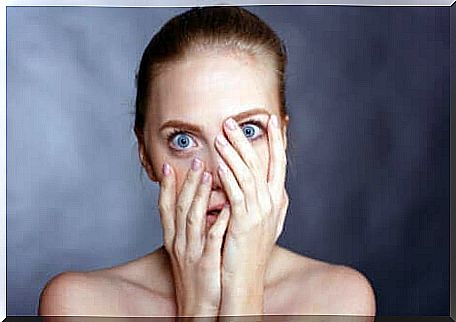 A woman with blue eyes covering her face.